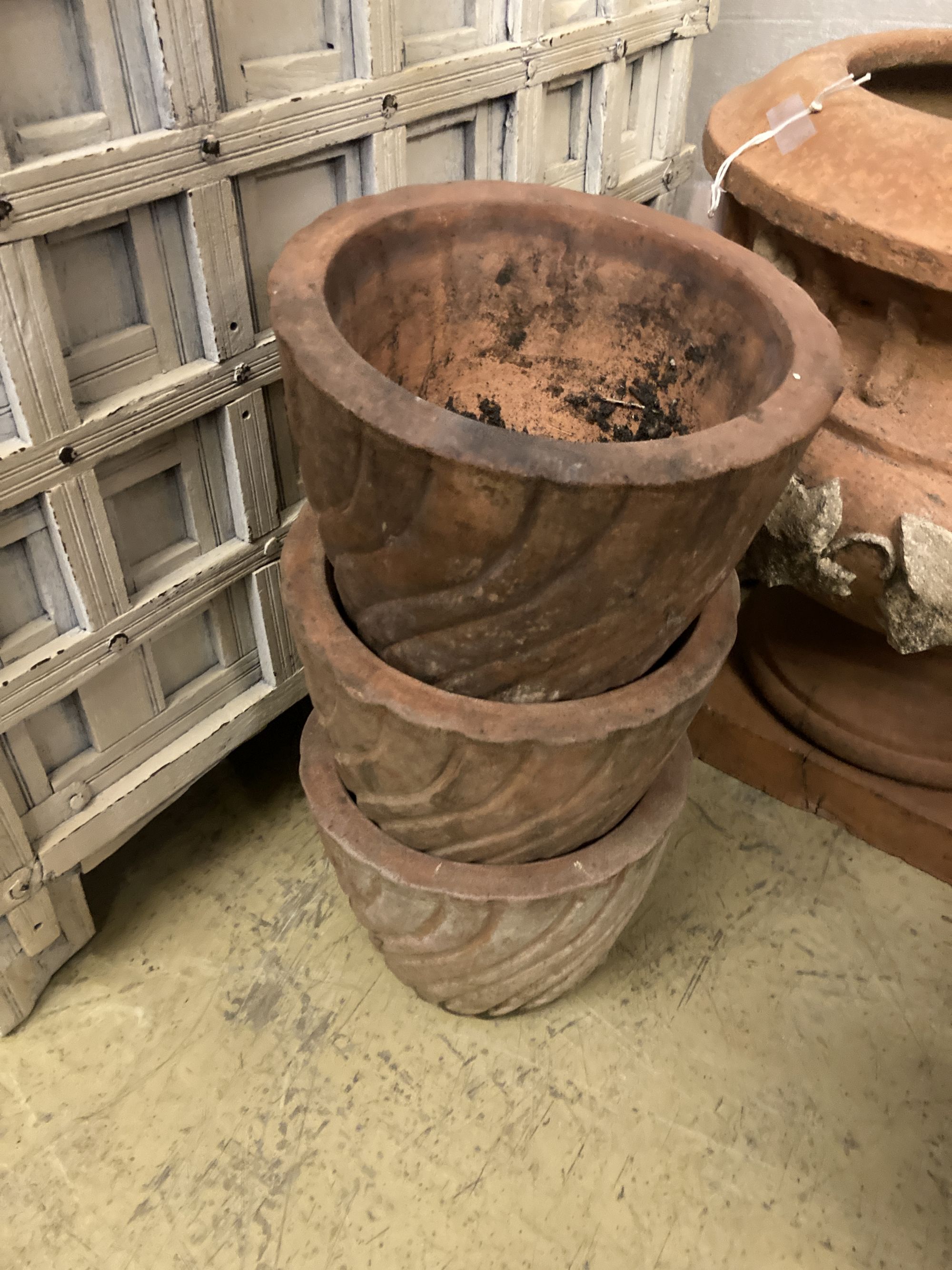 A circular terracotta garden planter on stand, diameter 56cm, height 50cm together with three smaller terracotta garden planters